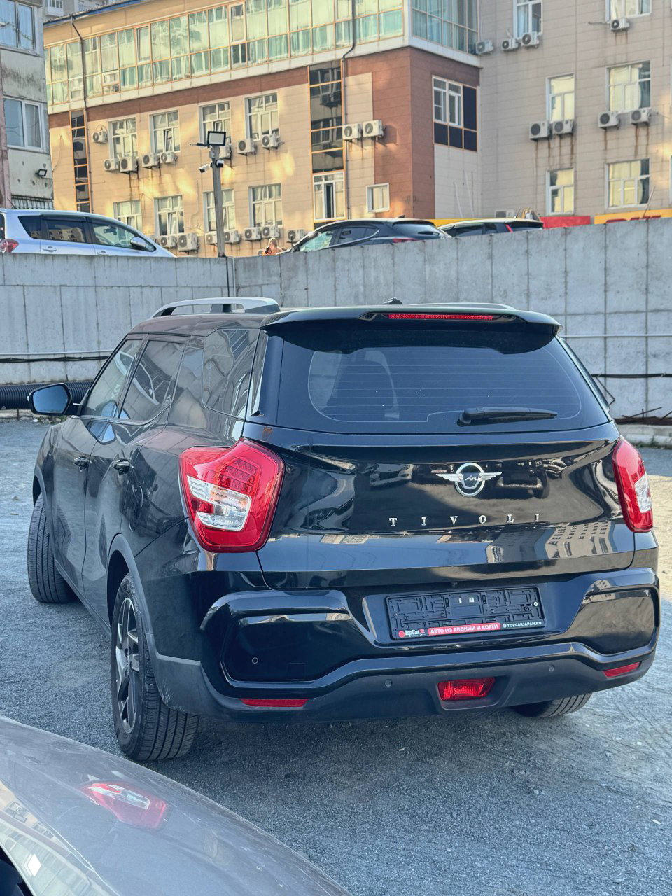 Задняя часть чёрного SsangYong Tivoli, видно эмблему и надпись TIVOLI; кадр показывает состояние бампера и задних фонарей.