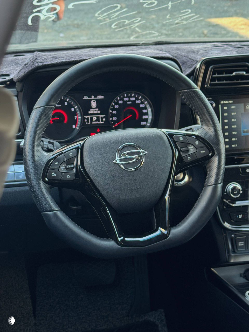 Рулевое колесо SsangYong Tivoli с кнопками управления мультимедиа и круиз-контролем; приборная панель частично видна на заднем плане.