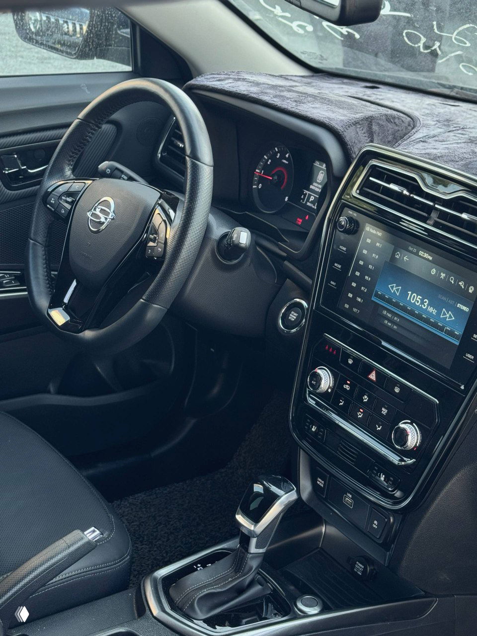 Общий вид салона SsangYong Tivoli со стороны водителя: кресла в чёрной обивке, центральный туннель и мультимедийная консоль.