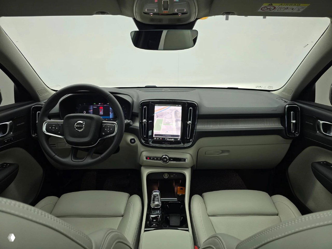 Салон Volvo XC40 — панорамный вид на торпедо, центральный сенсорный дисплей и передние сиденья светлого цвета, демонстрация состояния интерьера