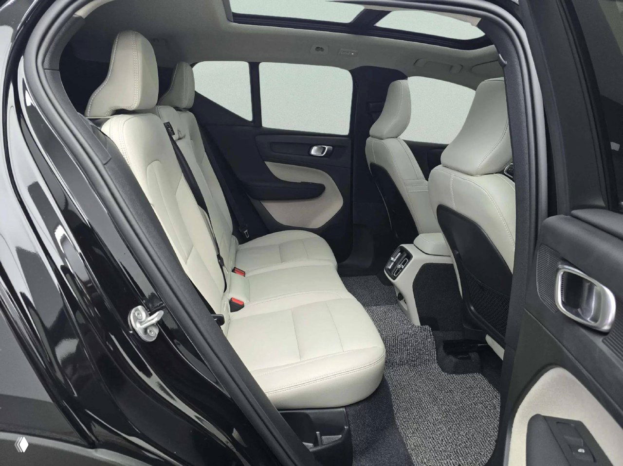 Задний ряд сидений Volvo XC40 — светлая кожаная обивка, простор для пассажиров и вид на центральный воздуховод и пол с ковриком