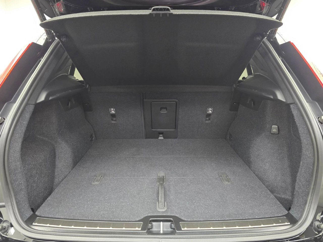 Багажное отделение Volvo XC40 — крупный план пустого багажника с открытой крышкой, ровный пол и петли обшивки багажного отделения