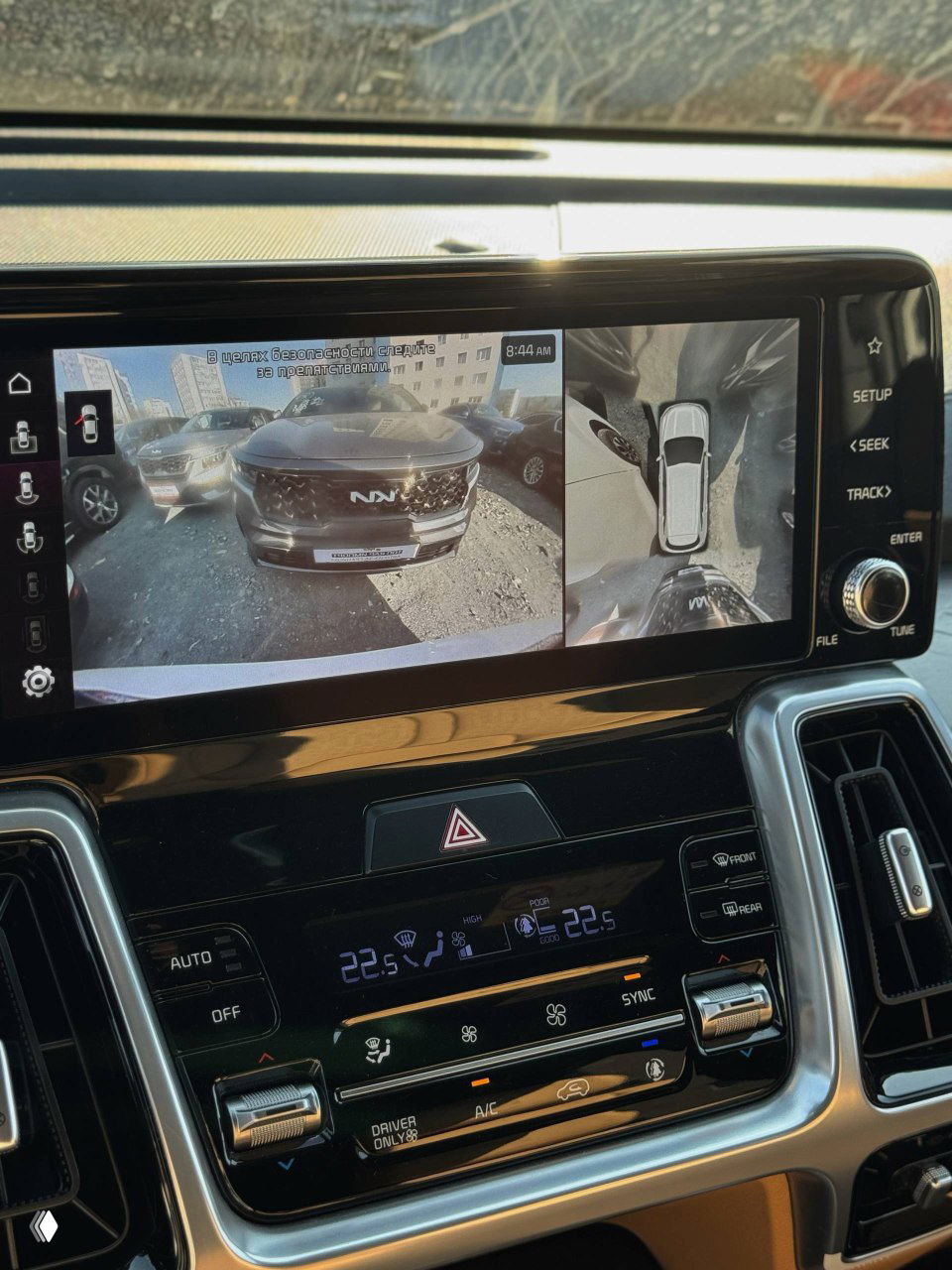 Экран мультимедиа KIA Sorento с изображением кругового обзора и парковочного пространства; видно отображение переднего бампера и обзор с камер.