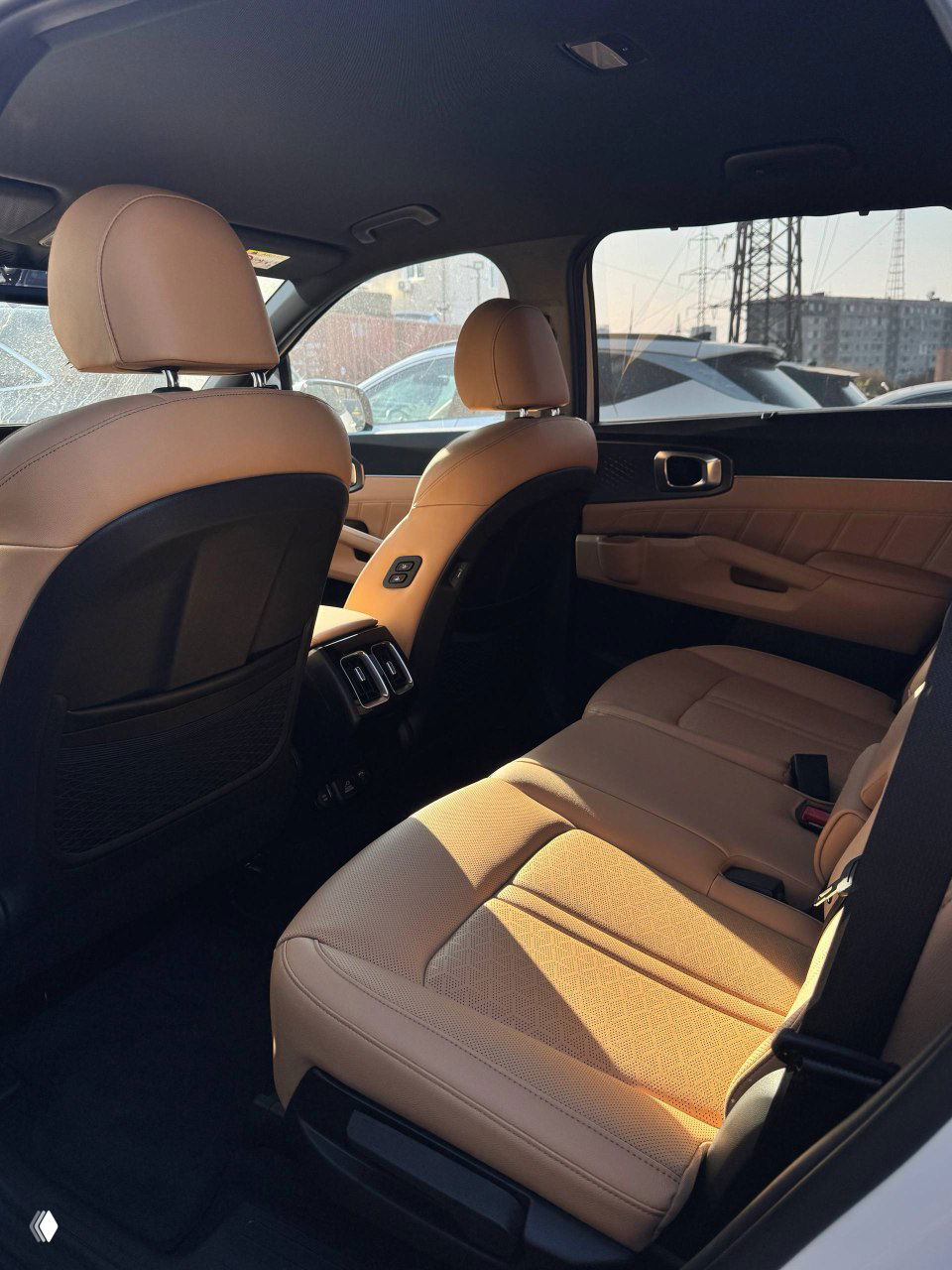 Задний ряд салона KIA Sorento: коричневая обивка, пространство для пассажиров и вид на задние воздуховоды, общий комфортный вид салона.