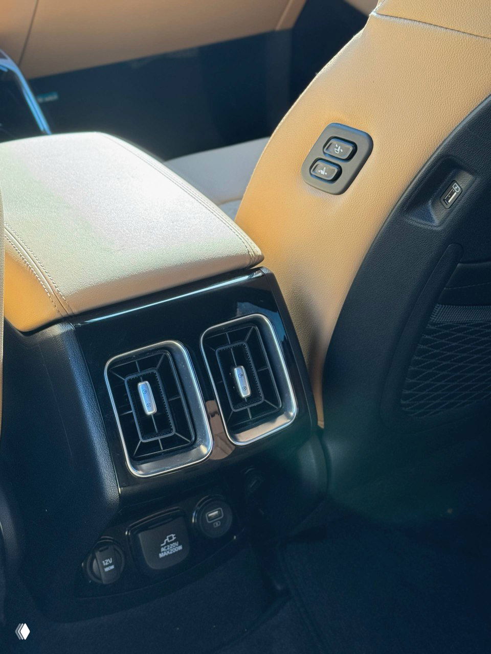 Крупный план задней консоли с вентиляционными дефлекторами, розетками и USB-портами для пассажиров; элементы удобства и отделки вблизи.