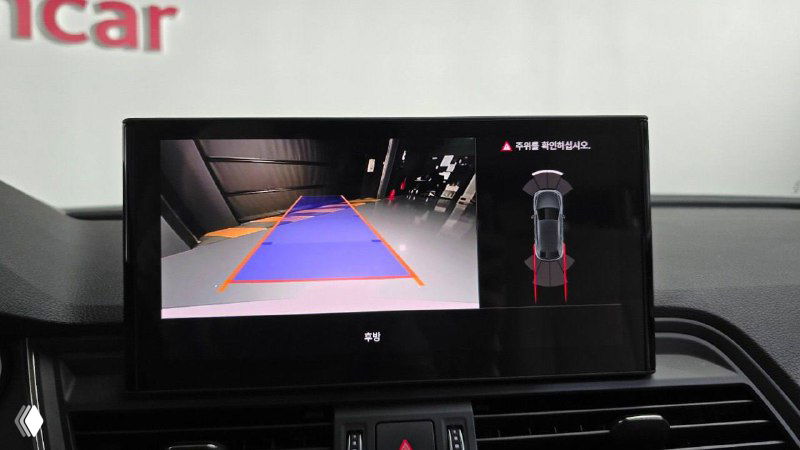 Экран парковочной камеры на дисплее мультимедиа с разметкой и обзором задней зоны — демонстрация системы помощи при парковке Audi Q5.