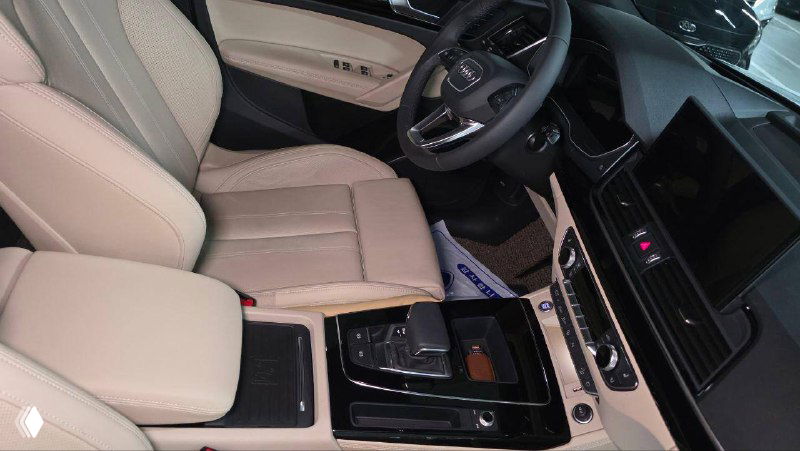 Интерьер Audi Q5: передние сиденья и центральная консоль с селектором передач, чёрно-бежевый дизайн и элементы управления.