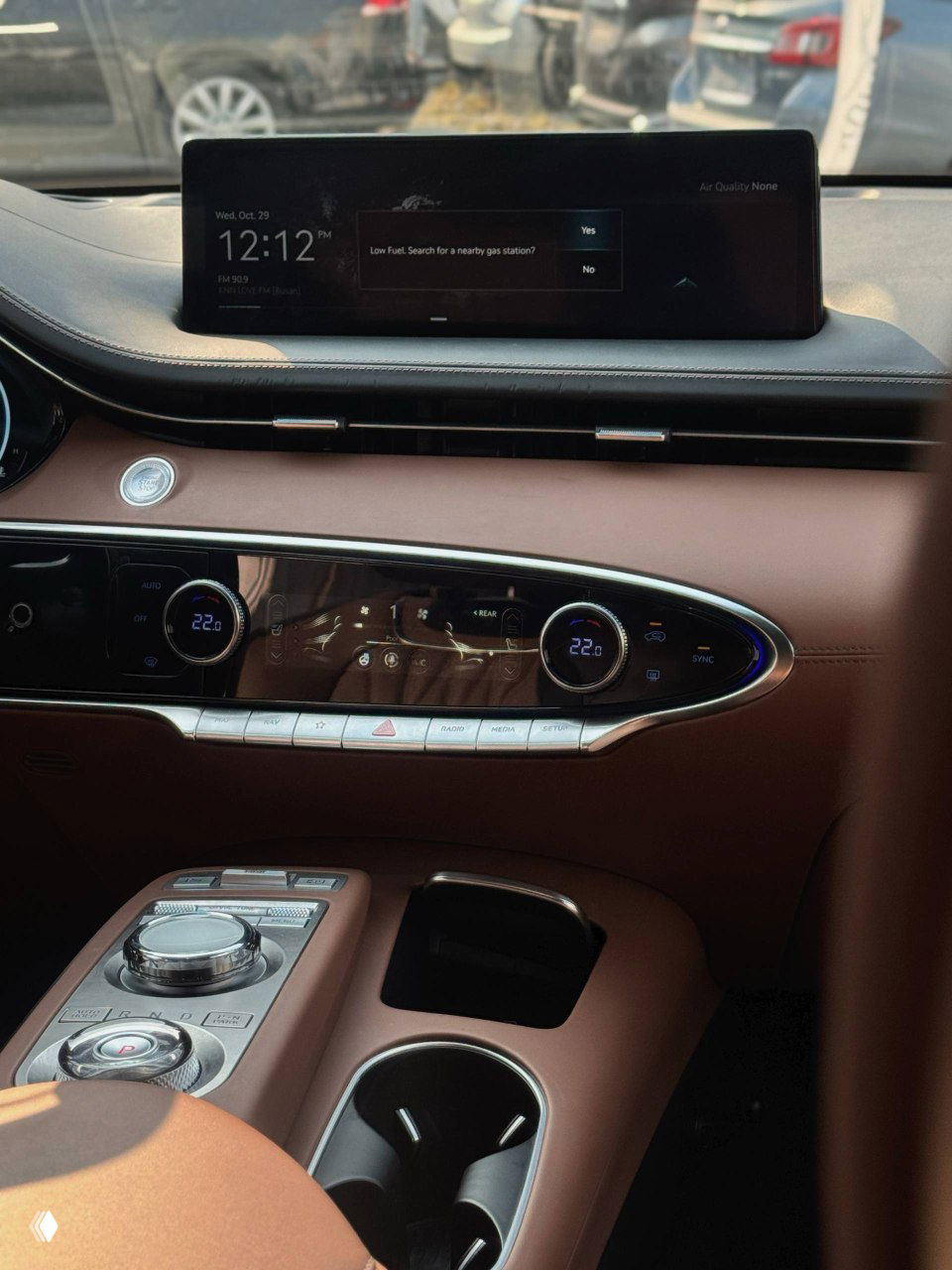 Центральная часть торпеды и дисплей мультимедиа Genesis GV70, коричневая отделка кожи и блестящие хромированные элементы на передней панели.