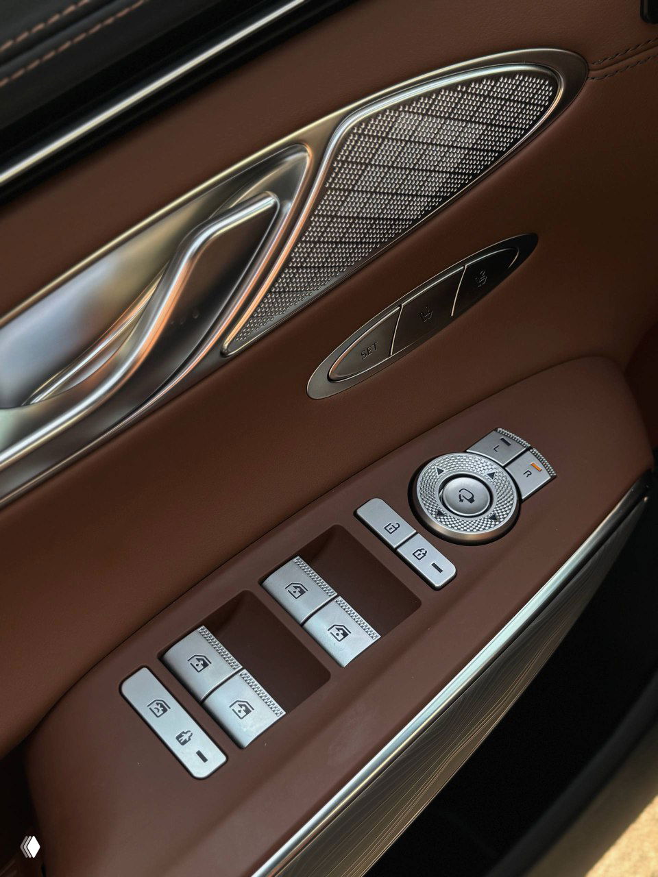 Дверная панель с блоком кнопок управления стеклоподъёмниками, подлокотником и динамиком; коричневая отделка и хромированные элементы видны крупно.