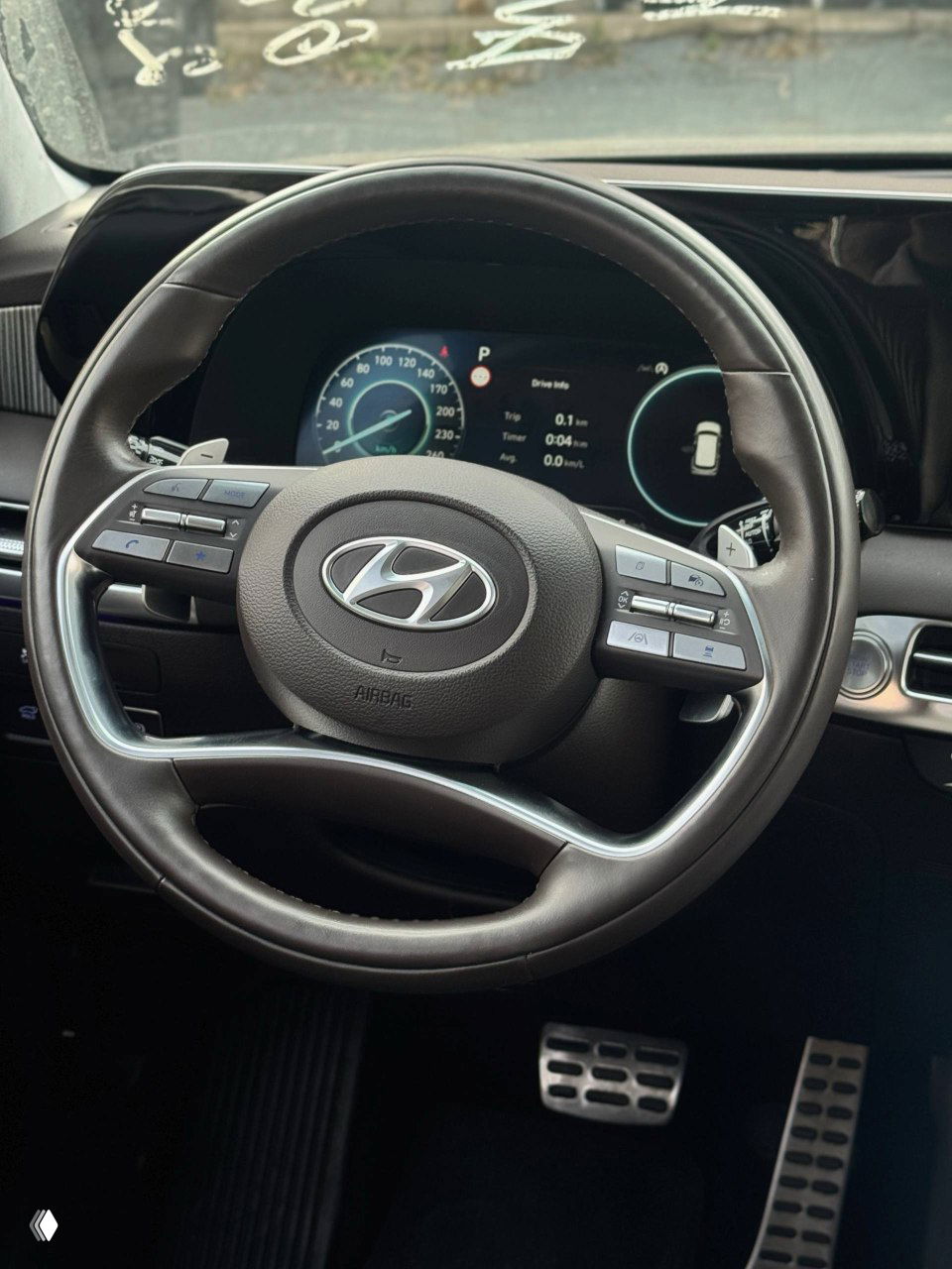 Крупный план рулевого колеса и приборной панели Hyundai Palisade: элементы управления на руле, цифровая приборная панель и логотип Hyundai в центре.