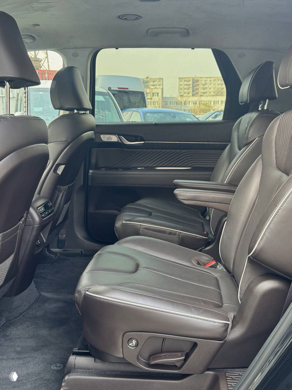 Средний ряд салона Hyundai Palisade: кожаные сиденья второго ряда, подлокотник и пространство для пассажиров, крупный план посадочных мест.