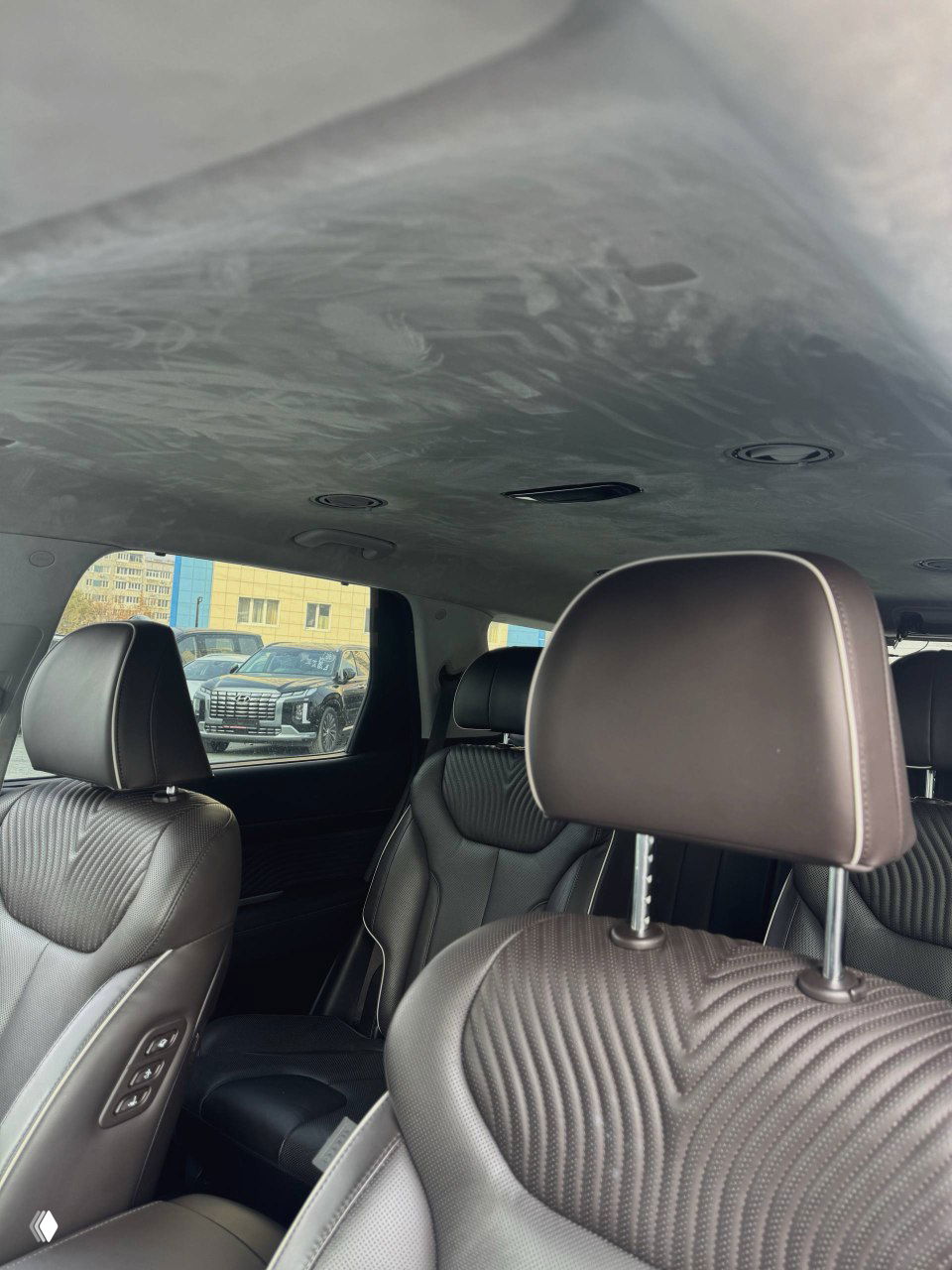 Крупный план передних сидений и потолка салона Hyundai Palisade: текстура обивки, подголовники и обзор внутреннего пространства автомобиля.