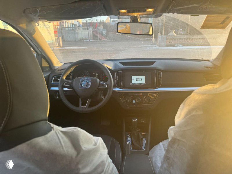 Интерьер Skoda Kamiq — общий вид на переднюю панель, центральную консоль и пассажирское сиденье, сиденья закрыты защитными чехлами.