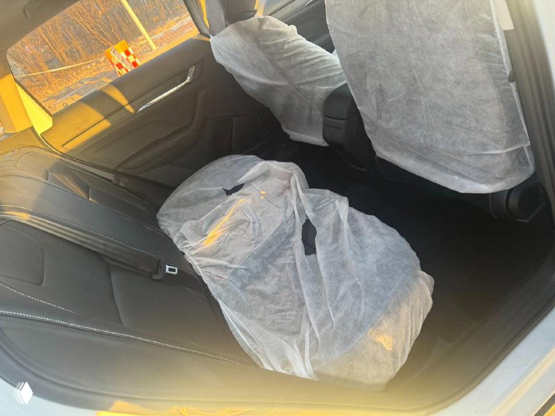 Задние сиденья Skoda Kamiq 2025 с упаковочными чехлами на креслах и упакованным аксессуаром на заднем сиденье, интерьер в зимнем освещении.