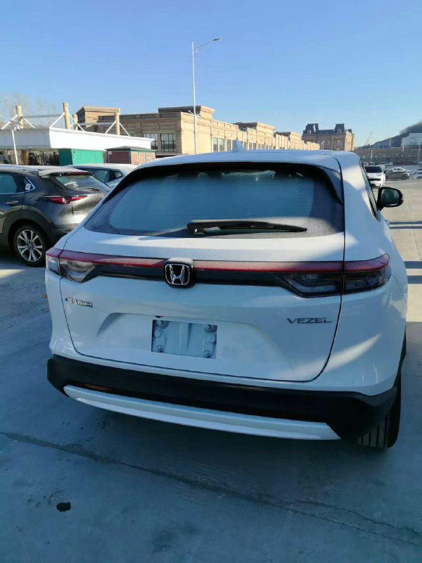 Задняя часть белого Honda Vezel 2026: багажник, фонари и шильдик Vezel, автомобиль на экспортной стоянке, без посторонних повреждений.