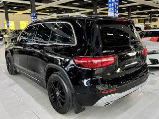 Задняя часть чёрного Mercedes GLB 180 2022 в автосалоне; вид на багажник, светодиодные фонари и хромированные элементы бампера на фоне стенда.