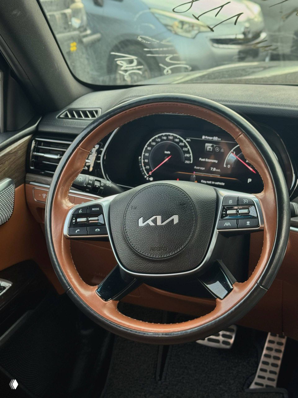 Руль KIA Mohave в коричневой кожаной отделке с логотипом KIA, на фоне приборной панели и элементов управления; интерьер в хорошем состоянии.