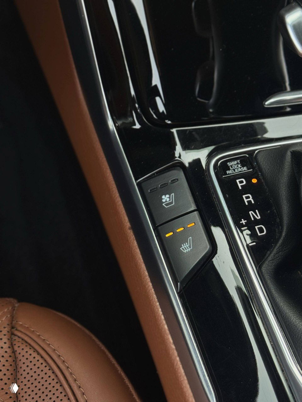 Крупный план кнопок управления обогревом и вентиляции сидений рядом с селектором передач — индикаторы работы подогрева активны.