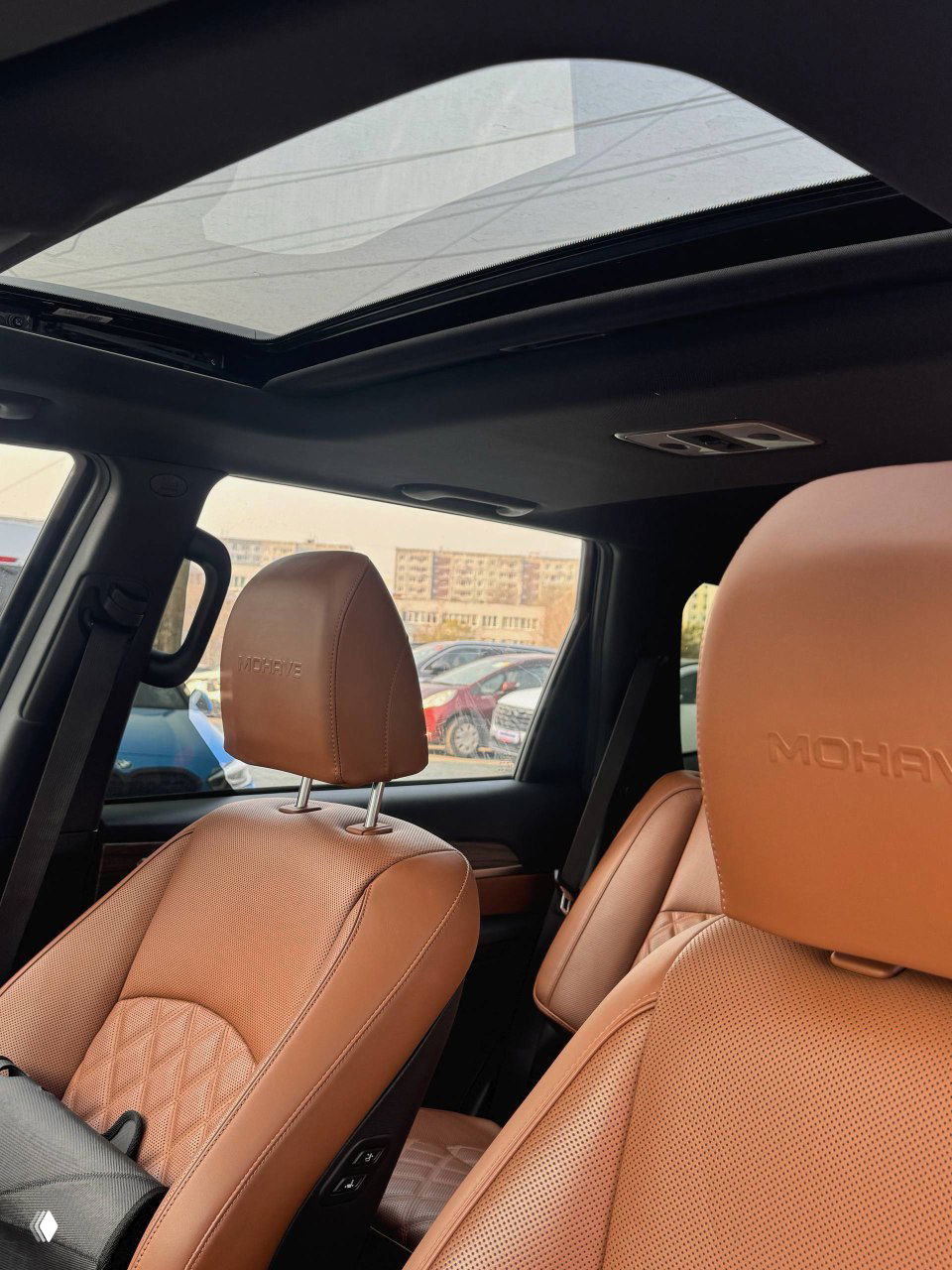 Люк и передние кресла KIA Mohave с рельефной коричневой кожей и вышитым логотипом MOHAVE на подголовниках; интерьер с панорамным люком.
