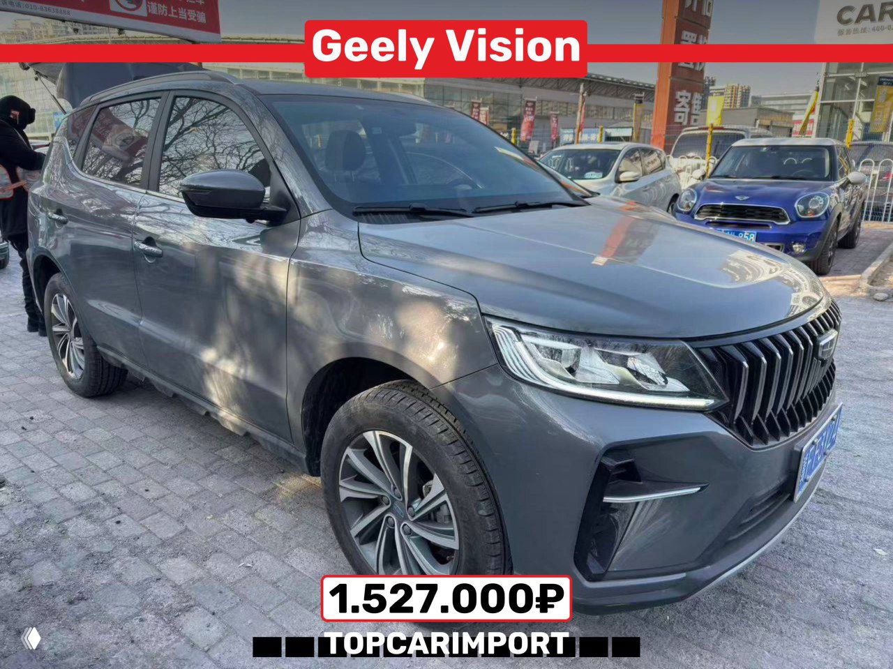 Geely Vision 2022 серого цвета, боковой вид на улице у дилерской площадки, на изображении указана цена 1.527.000₽ и логотип TOPCARIMPORT.