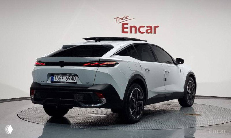 Задний ракурс белого Peugeot 408 в шоуруме Encar: показана кормовая часть, фонари и профиль кросс-лифтбека с подчеркнутой формой крыши.