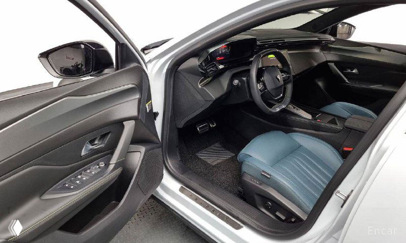 Открытая дверь и вид на водительский проём Peugeot 408: кожа дверной обивки, порог и переднее сиденье, показаны материалы отделки салона.