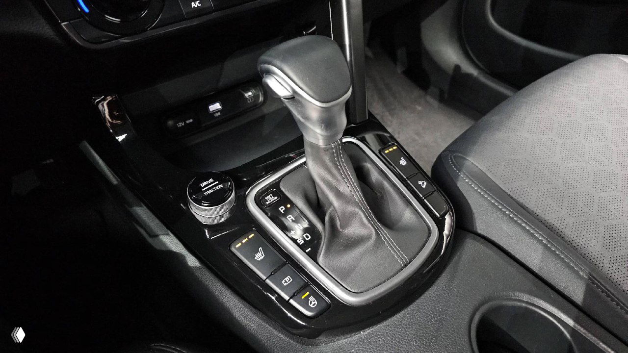 Крупный план селектора коробки передач вариатор (CVT) KIA Seltos 2023 с кнопками подогрева сидений и управляющими элементами рядом с подстаканником.