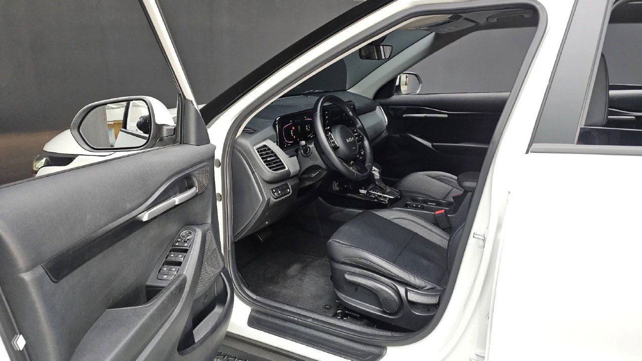 Вид водительской двери и переднего сиденья KIA Seltos 2023: дверная панель, зеркало, элементы управления стеклоподъемниками и обивка салона.