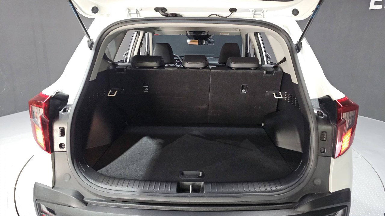 Багажник KIA Seltos 2023 с открытой пятой дверью: просторный отсек для вещей, ровное покрытие пола и вид на сложенные задние сиденья.