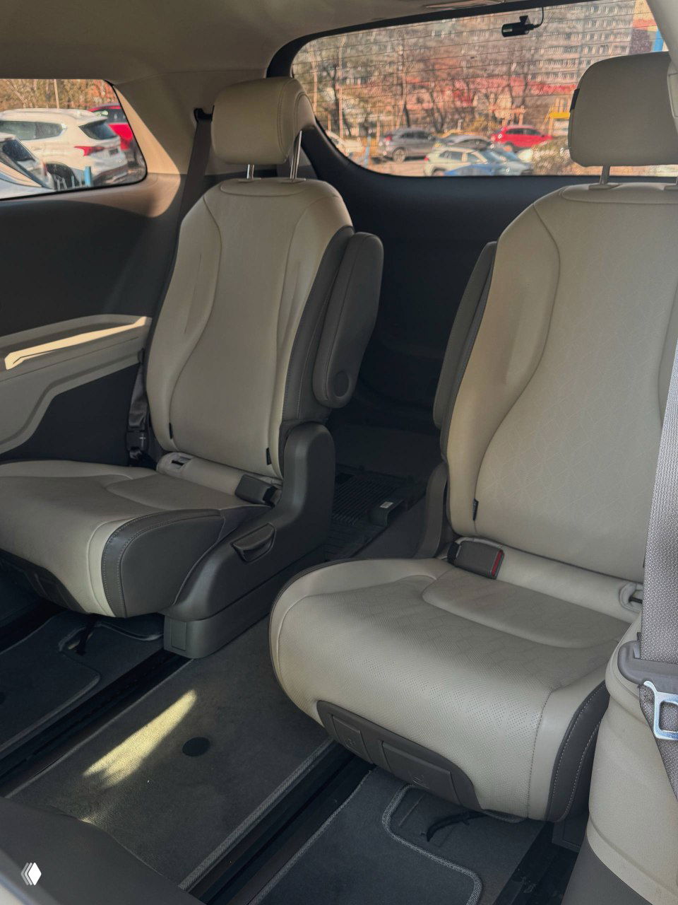 Вид на второй ряд сидений KIA Carnival с акцентом на посадочные места и пространство салона, чистые сиденья и боковые панели интерьера.