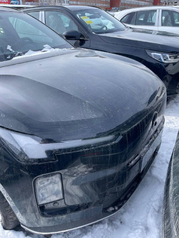 Крупный план капота и передней части Volvo XC-70 2025 в снегу, видна пыль, лед и мелкие следы — фото с автоплощадки для покупателей и оценки состояния.