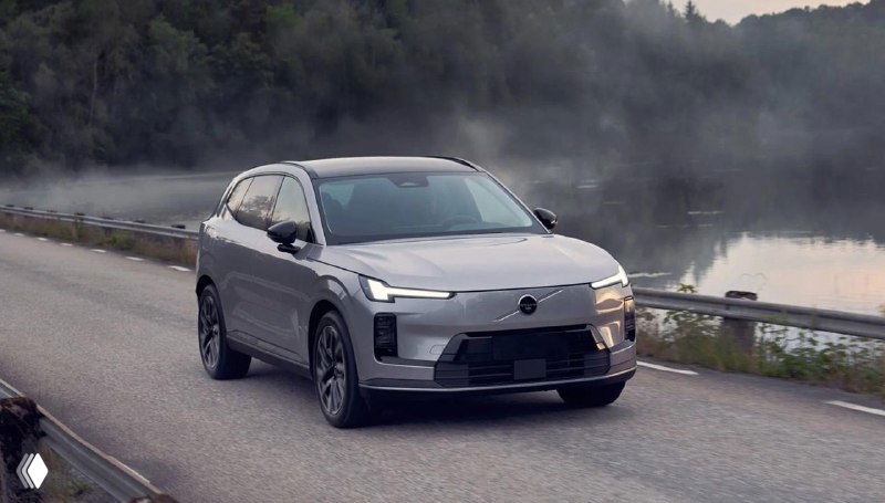 Серый Volvo в движении по трассе у озера при раннем тумане, демонстрация поведения автомобиля при поездках на дальние расстояния и в разных погодных условиях.