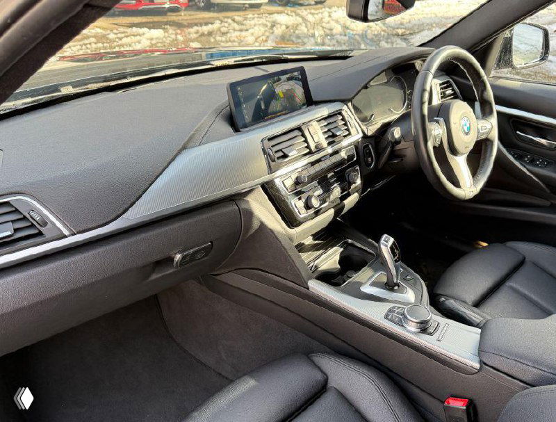 Салон BMW 3 Series: передняя панель, центральная консоль, руль справа, экран мультимедиа и кожаные сиденья в крупном плане.