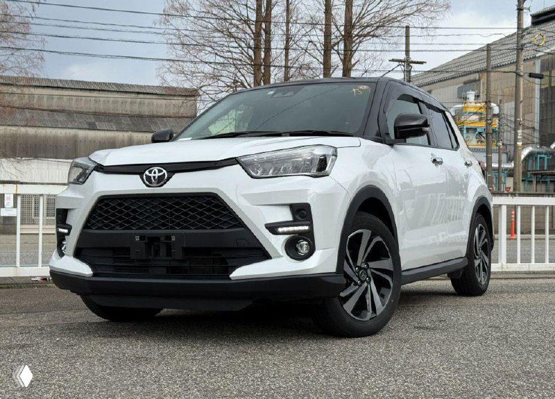 Белый Toyota Raize на стоянке, вид спереди-слева; компактный городской кроссовер, хорошо видны фары и передний бампер.