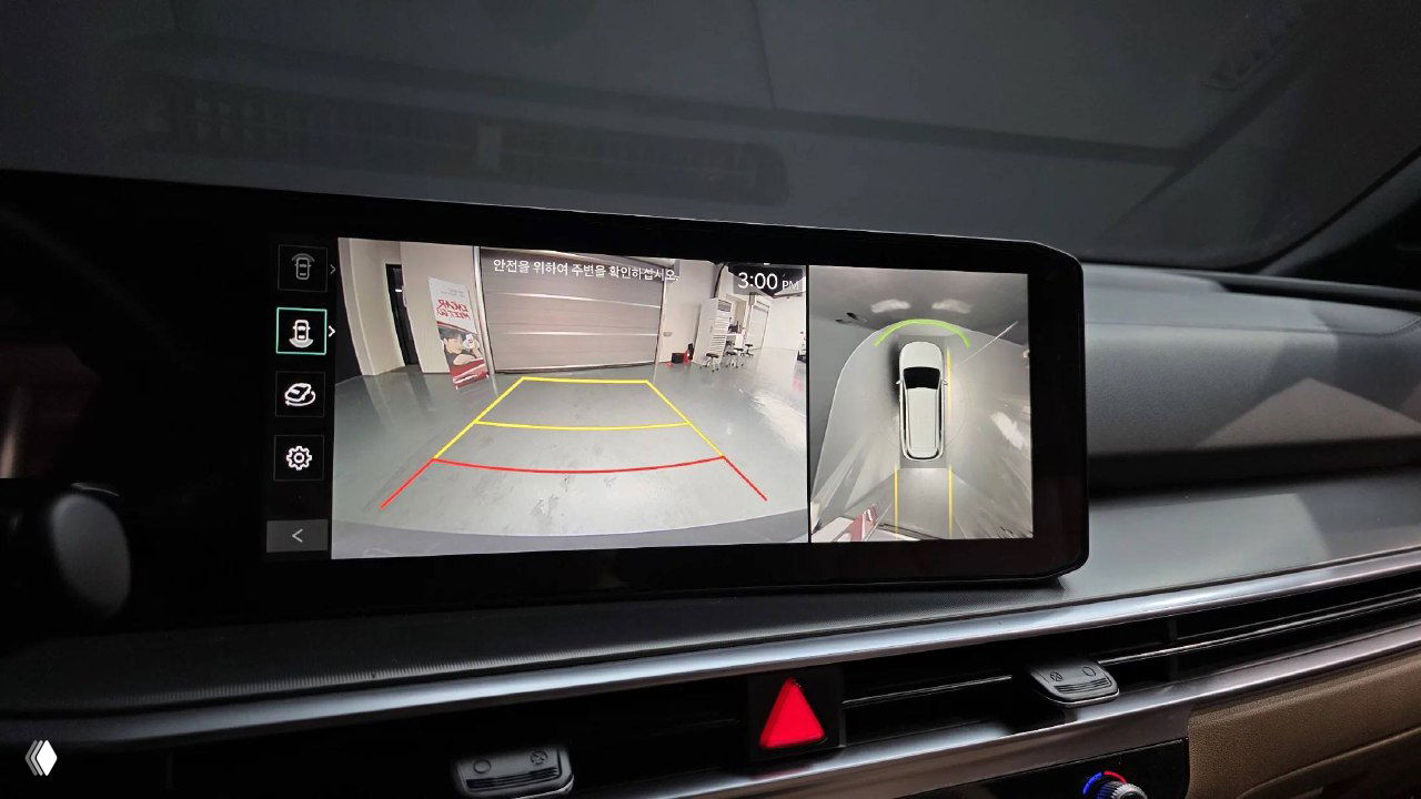 Экран камер заднего вида и кругового обзора автомобиля KIA Sorento 2024: изображение парковочной зоны и разметки на дисплее мультимедиа.