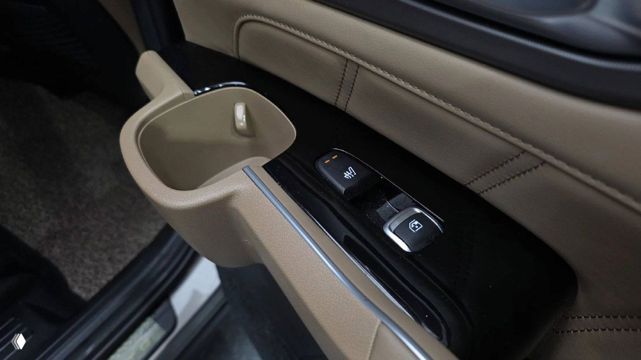 Крупный план боковой панели двери с подстаканником и органами управления стеклоподъёмниками в бежевом исполнении KIA Sorento 2024.