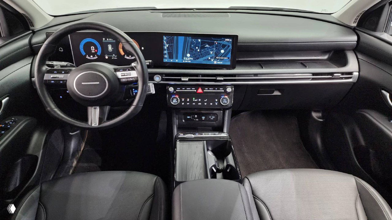 Интерьер Hyundai Tucson: панель приборов, широкая мультимедийная панель и рулевое колесо, чёрная отделка салона и центральная консоль в одном кадре.