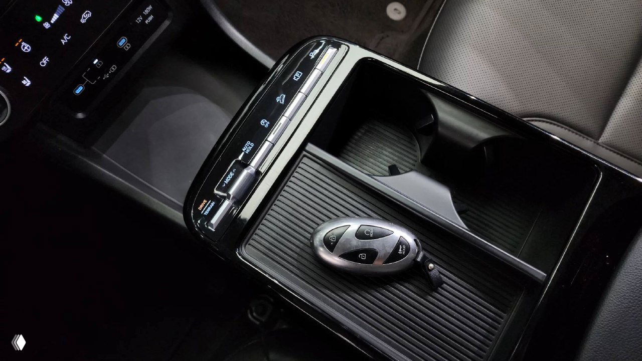 Деталь центрального подлокотника и отверстия для стаканов, на панели лежит оригинальный смарт-ключ Hyundai в интерьере Tucson.