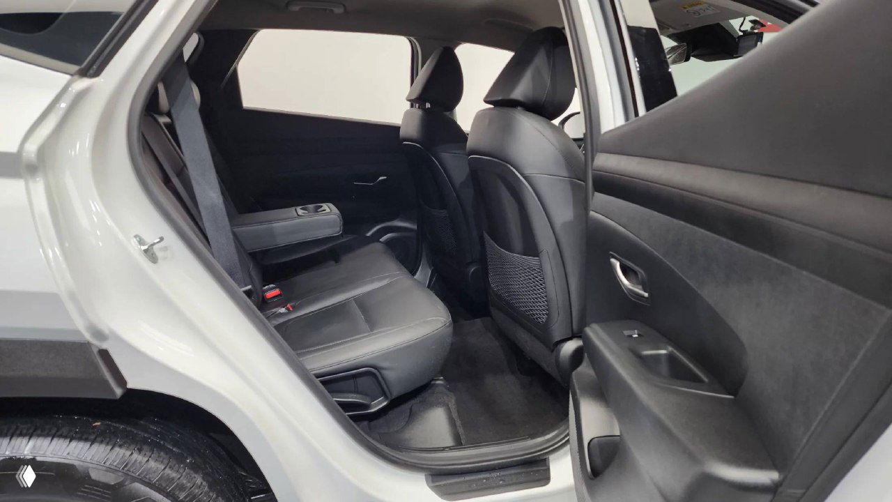 Вид на задний ряд сидений Hyundai Tucson: чёрная обивка, складной подлокотник, простор для пассажиров и общий комфорт задней зоны салона.