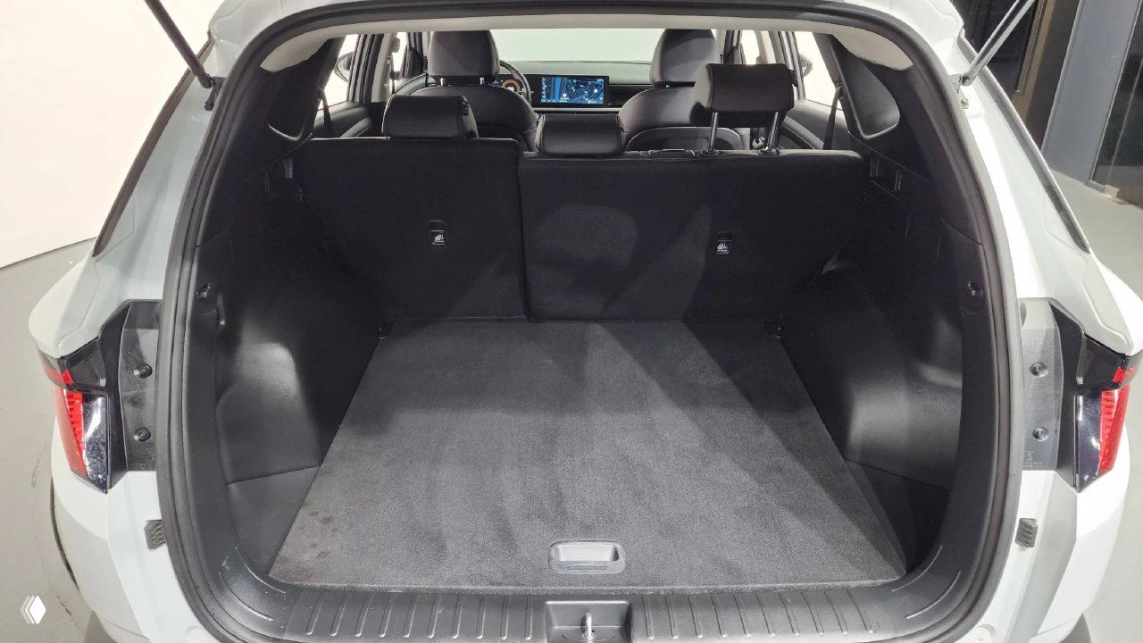 Открытый багажник рестайлингового Hyundai Tucson с ровным полом и пространством для поклажи; видна обшивка и задняя часть салона из багажника.