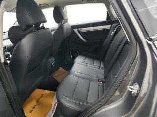 Задние сиденья Geely Coolray 2025 с тёмной обивкой: демонстрация пространства для пассажиров, состояние сидений и дверной проём со светлым напольным ковриком.