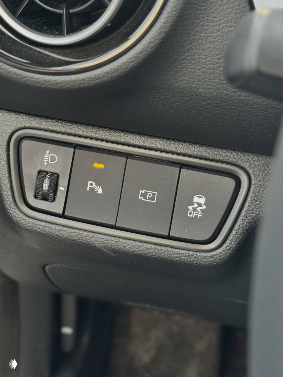 Блок кнопок ассистентов водителя и регулировок в салоне KIA K3: парковочные сенсоры, камера и системы стабилизации рядом с воздуховодом.