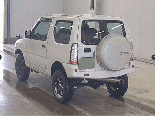 Suzuki Jimny 2011, вид сзади на складе аукциона; запасное колесо на двери, задняя часть и подвеска с повышенным клиренсом.