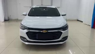 Фронтальный вид белого Chevrolet Cruze 2021 в салоне: пропорции кузова, решетка радиатора и фары видны спереди в студийном освещении.