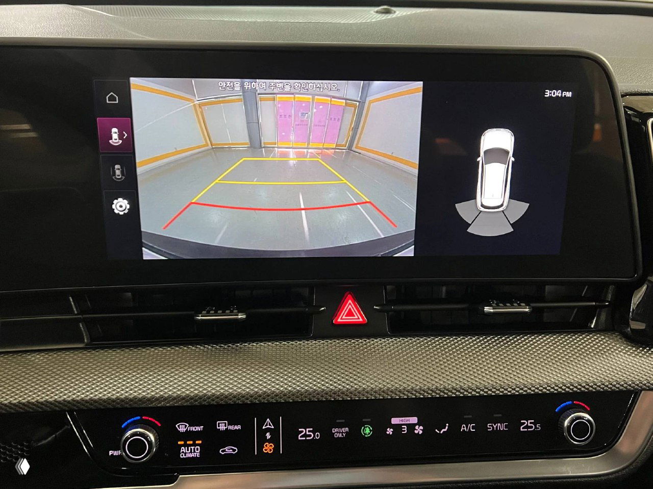 Крупный план информационного и парковочного экрана на центральной консоли KIA Sportage 2023 с изображением камеры заднего вида и индикацией парктроника.