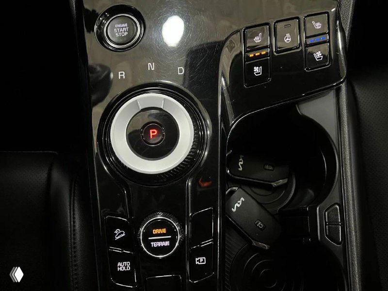 Детальный вид центральной панели и селектора режимов привода KIA Sportage 2023, крупный план кнопок управления и подстаканников в консоли.