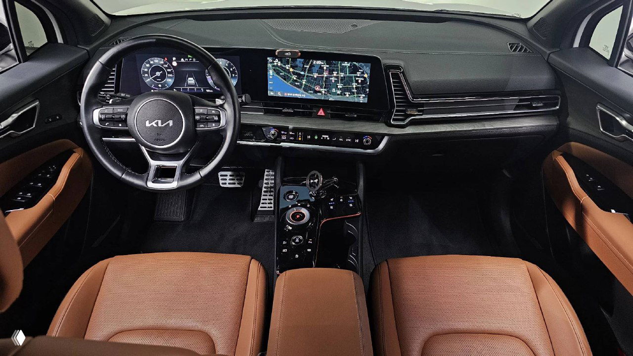 Интерьер KIA Sportage 2024: коричневая кожаная отделка сидений, панель приборов и большой центральный дисплей — салон в хорошем состоянии.