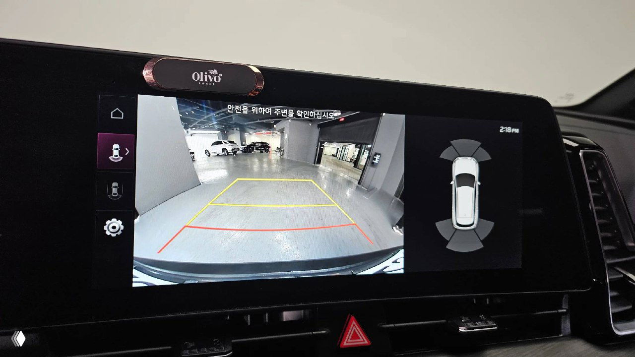 Экран камеры заднего вида KIA Sportage в режиме парковки, на экране видна разметка парковочного места и обзор заднего пространства автомобиля.