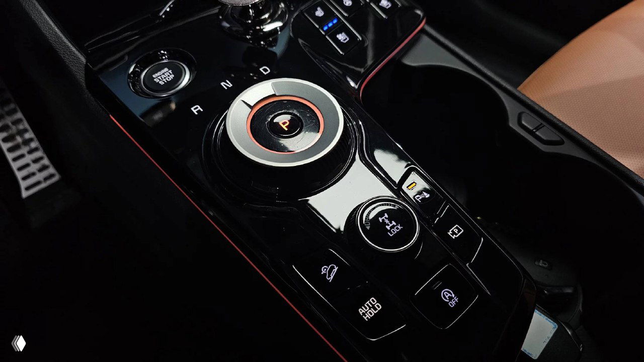 Блок управления на центральной консоли KIA Sportage: селектор режимов трансмиссии, кнопки паркинга и системы удержания, глянцевая отделка с акцентной подсветкой.