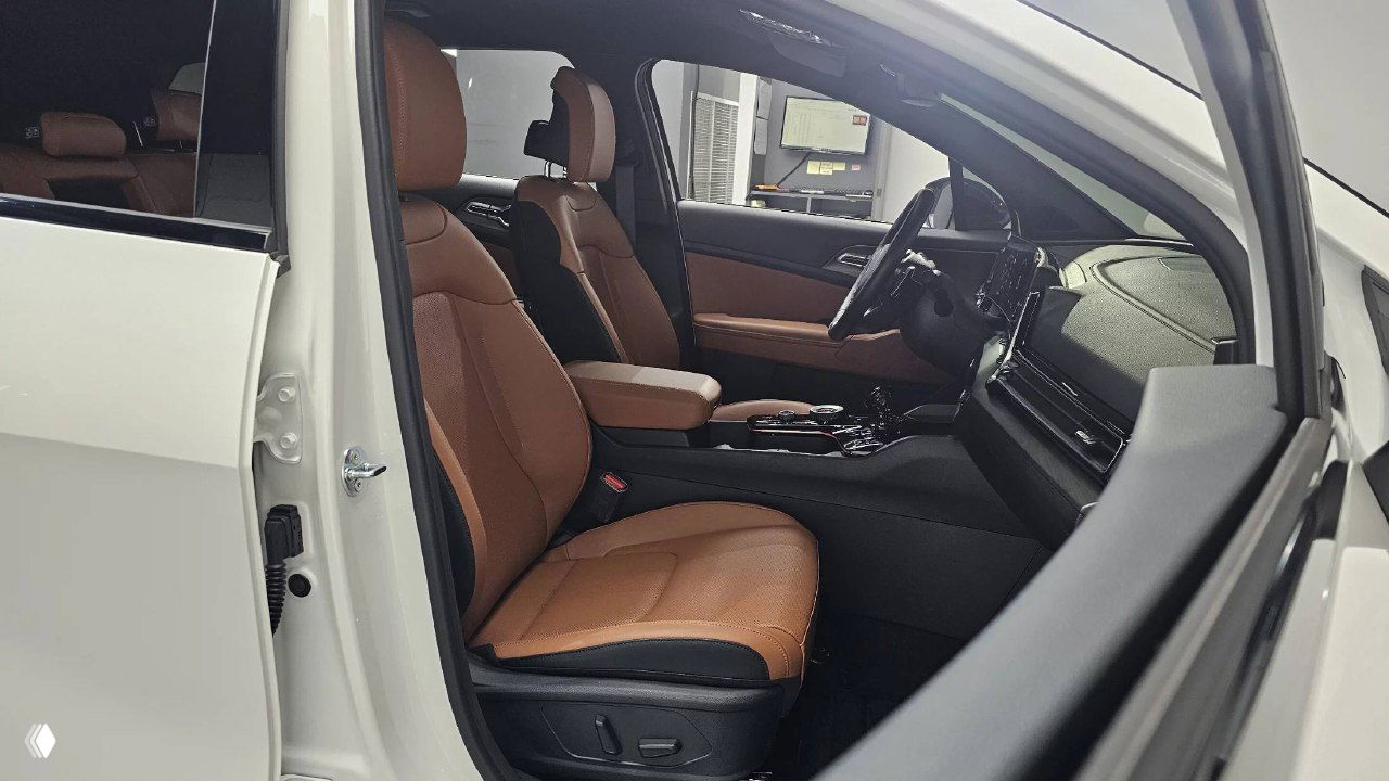 Передние сиденья и дверной проём KIA Sportage с открытой дверью, видно комфортную коричневую обивку и пространство передней части салона.